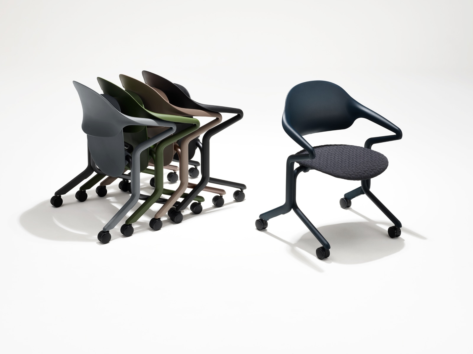 Quatre sièges gigognes Fuld dans différentes couleurs et finitions, imbriqués, à côté d'un siège Fuld seul, en finition Nightfall et textile 3D Knit.